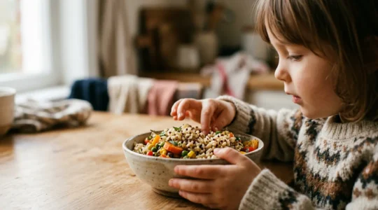 Mains d'enfant tenant un bol de céréales complètes colorées avec des fruits frais