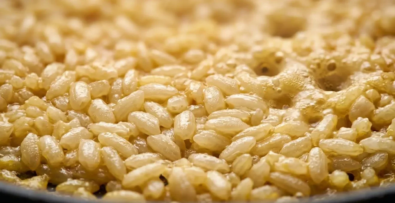 Gros plan macro sur la surface du riz en cuisson montrant les cratères de vapeur et la texture des grains