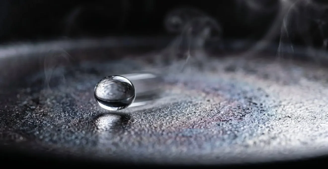Goutte d'eau formant une sphère parfaite flottant sur une surface de poêle ultra-chaude démontrant l'effet Leidenfrost